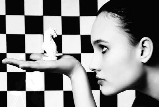 Description de l'image par IA : Femme tenant un petit oiseau blanc devant une grille en noir et blanc.