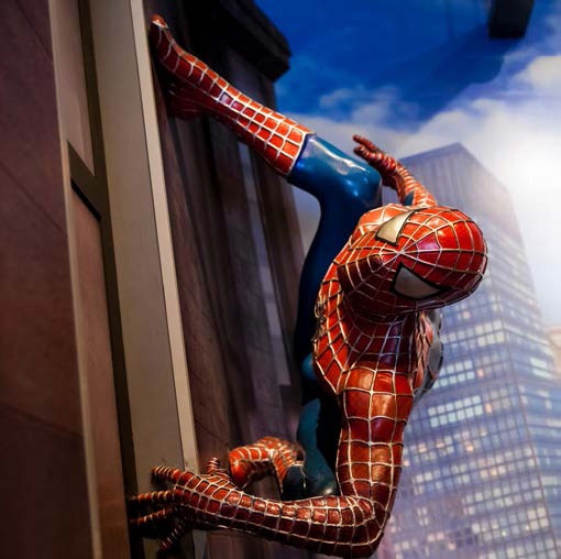 Description de l'image par IA : Homme en costume de Spiderman grimpe sur un mur avec une ville en arrière-plan.