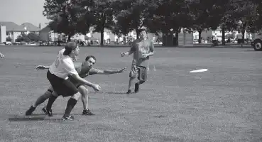 Description de l'image par IA : Trois jeunes hommes jouent au frisbee dans un parc. L'un d'eux lance le frisbee tandis que les deux autres courent pour l'attraper.