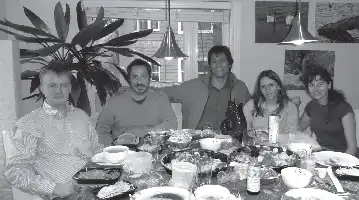 Description de l'image par IA : Cinq personnes assises autour d'une table avec des plats de sushis et des boissons, célébrant un événement.