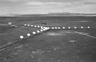 Description de l'image par IA : Nombreuses antennes circulaires disposées en Y dans un désert, avec montagnes au loin.