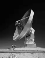 Description de l'image par IA : Télécope spatial géant dans désert, deux personnes à côté.
