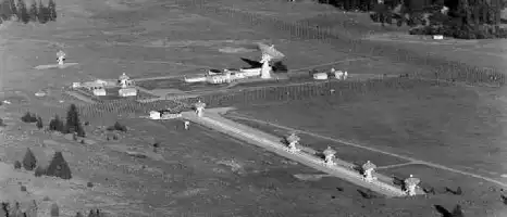 Description de l'image par IA : Aérodrome avec plusieurs antennes et structures, incluant un grand radiotélescope.