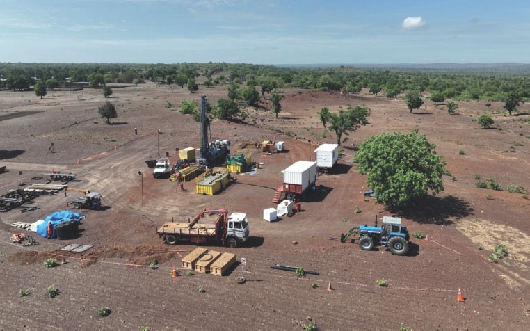 Description de l'image par IA : Champ aride avec divers équipements de forage, camions et tracteurs.