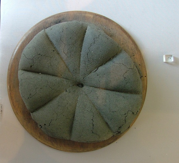 Description de l'image par IA : Un pain en forme de roue avec des quartiers séparables, retrouvé intact à Pompéi.