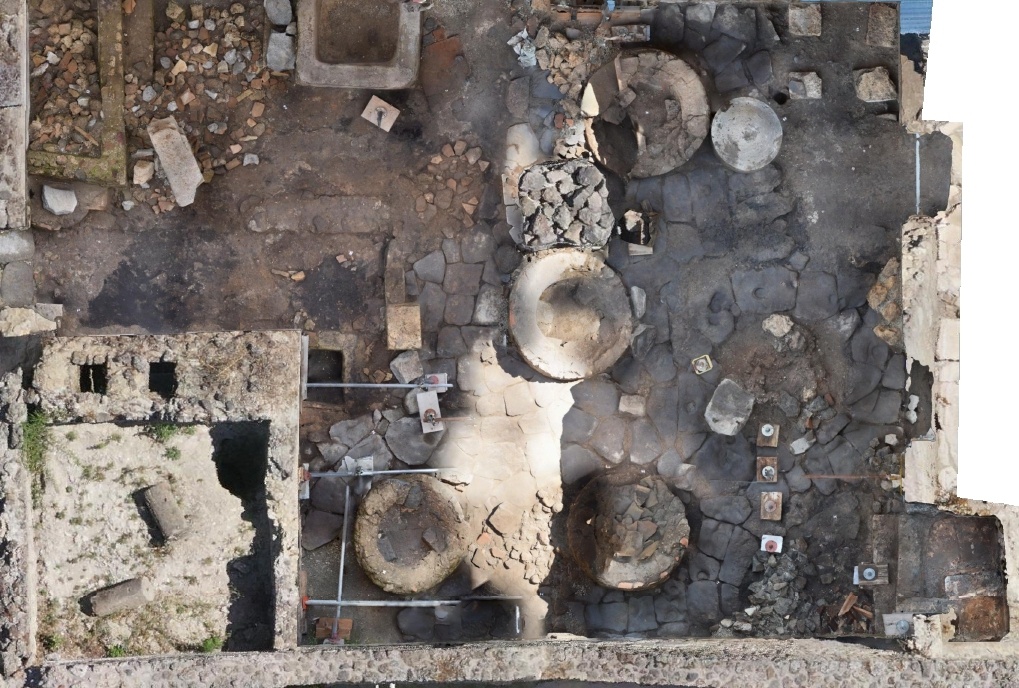 Description de l'image par IA : Découverte archéologique avec bases de meules, cuve et four.
