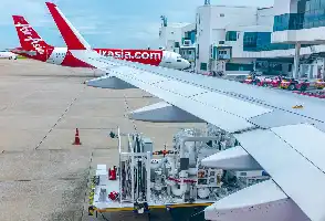 Description de l'image par IA : Avion AirAsia au sol avec une station de ravitaillement en carburant.