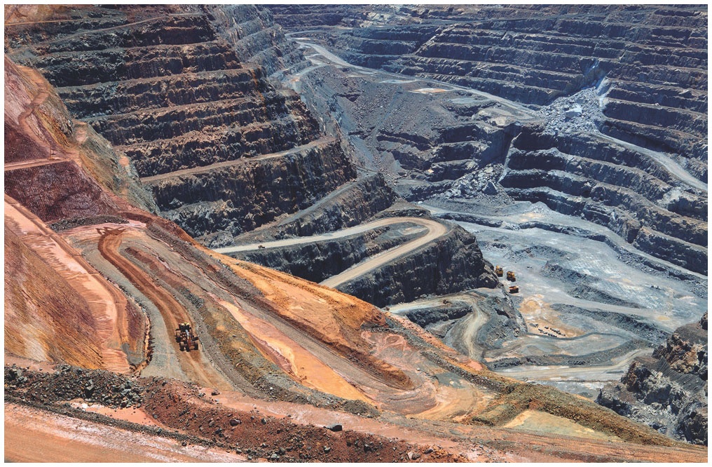 Description de l'image par IA : Grandes terrasses d'une mine à ciel ouvert avec des routes sinueuses et des zones de terre dénudée.